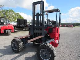 Red forklift on a paved area with other vehicles in the background